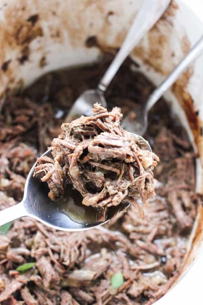 shredded beef in crock pot in a spoon