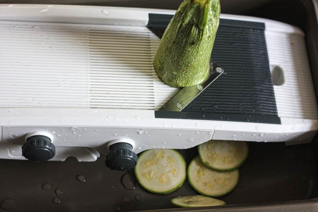 slicing zucchini on the mandoline