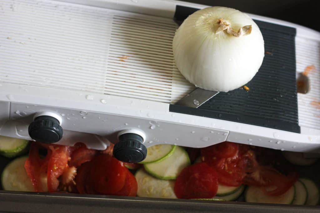 slicing white onion on the mandoline