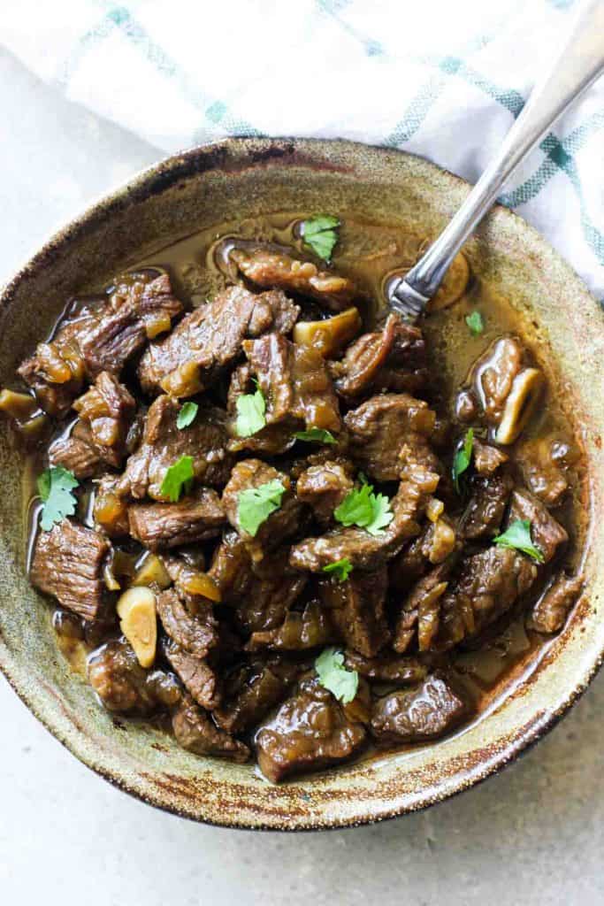 beef stew meat in onion gravy with chopped cilantro on top