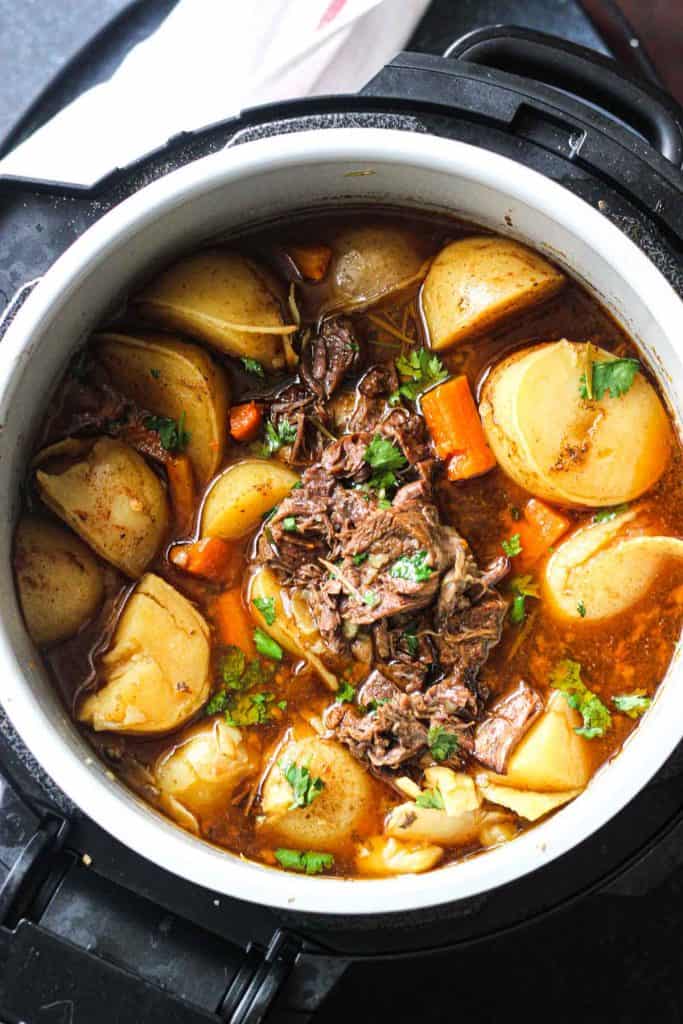 coked beef pot roast in pressure cooker with potatoes and carrots