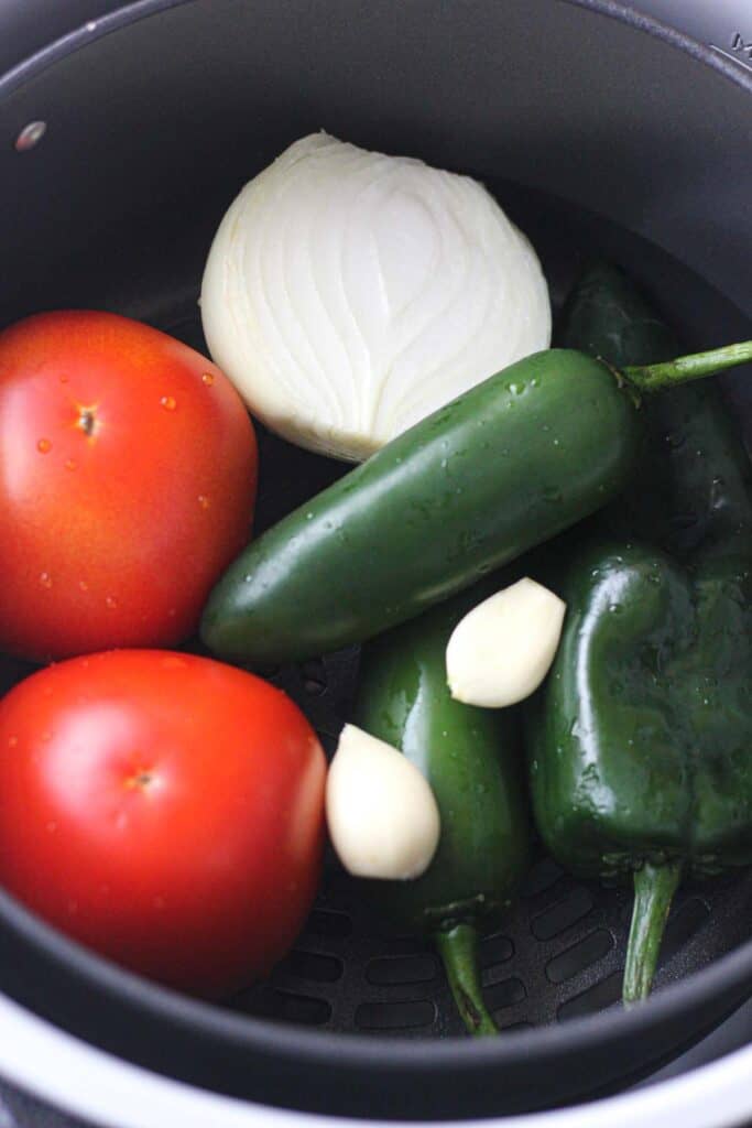 fresh tomatoes, pepers, onions and garlic in the ninja foodi air fryer basket