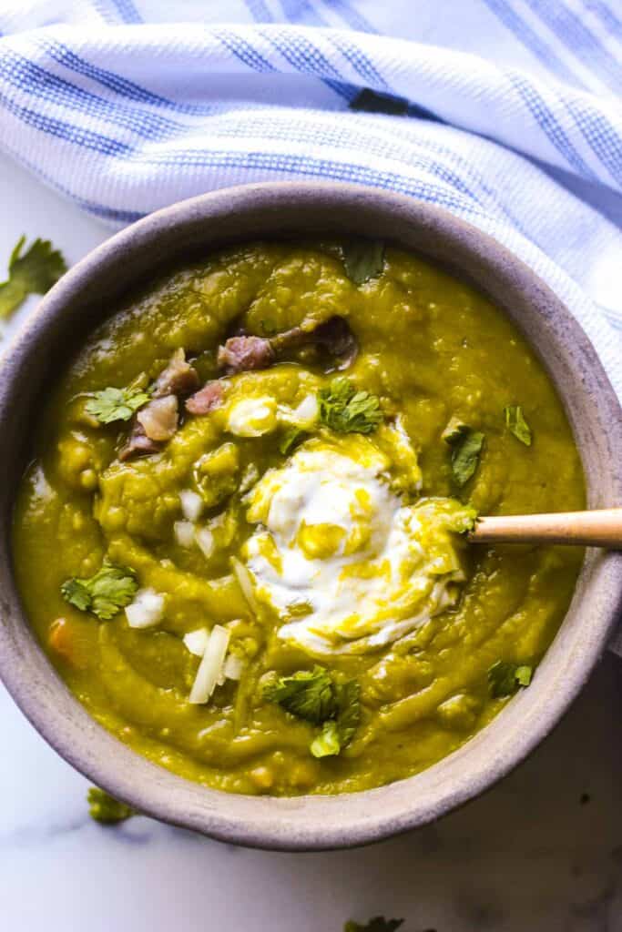 a bowl of split pea soup with cilantro and sour cream on top
