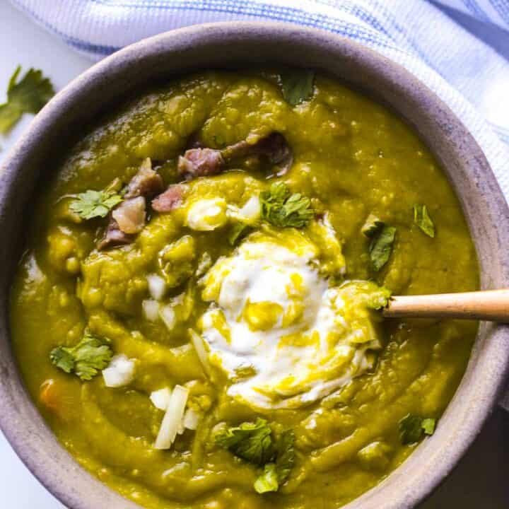 a bowl of split pea soup with cilantro and sour cream on top
