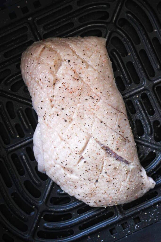 raw duck breast in the air fryer basket before cooking