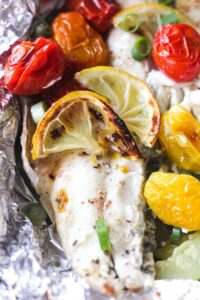 close picture of branzino fish with roasted cherry tomatoes on top