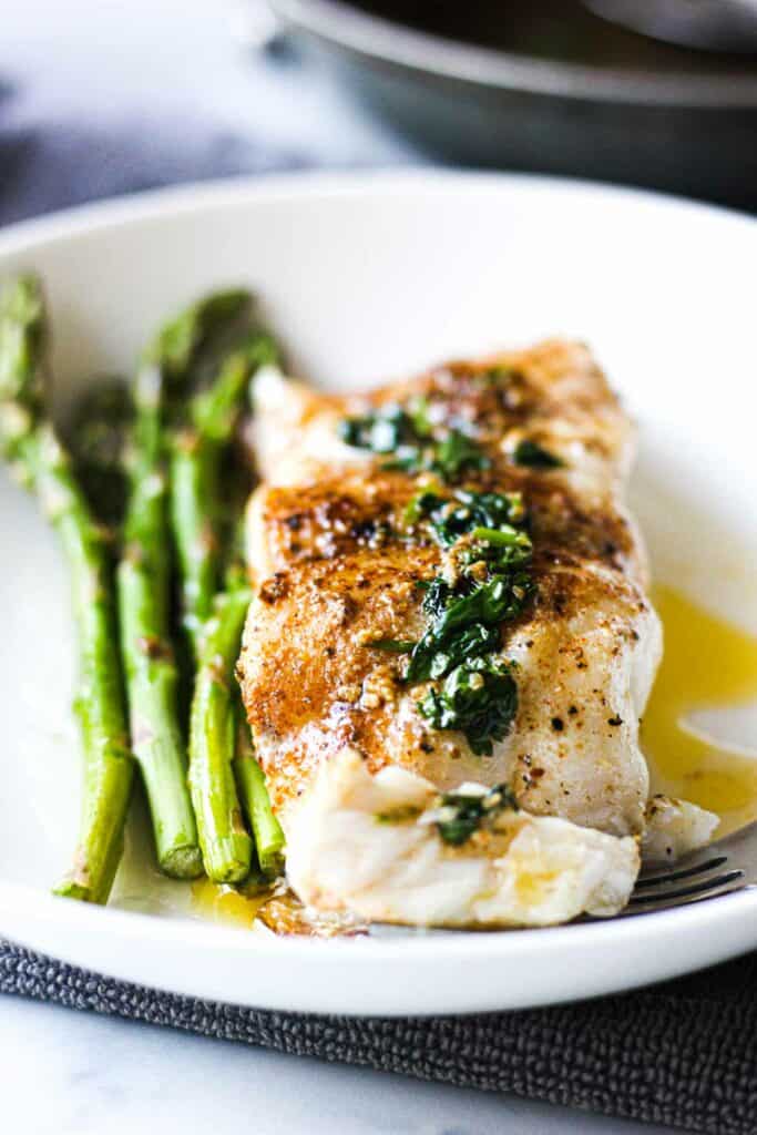 pas seared grouper on a white plate with lemon butter sauce