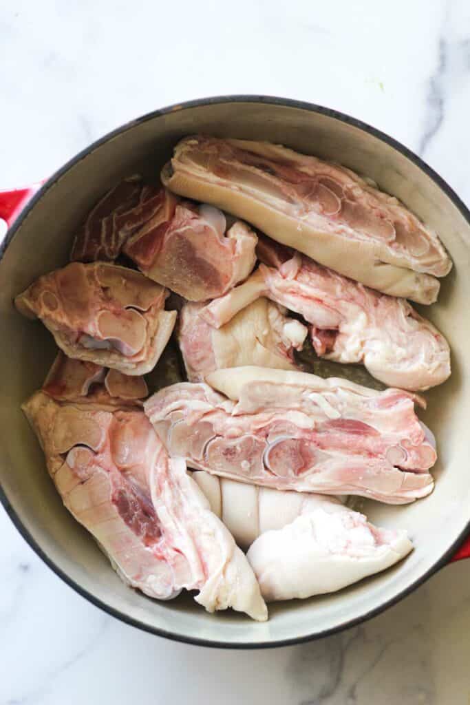 sliced raw pork with bones in the cast iron pot before cooking
