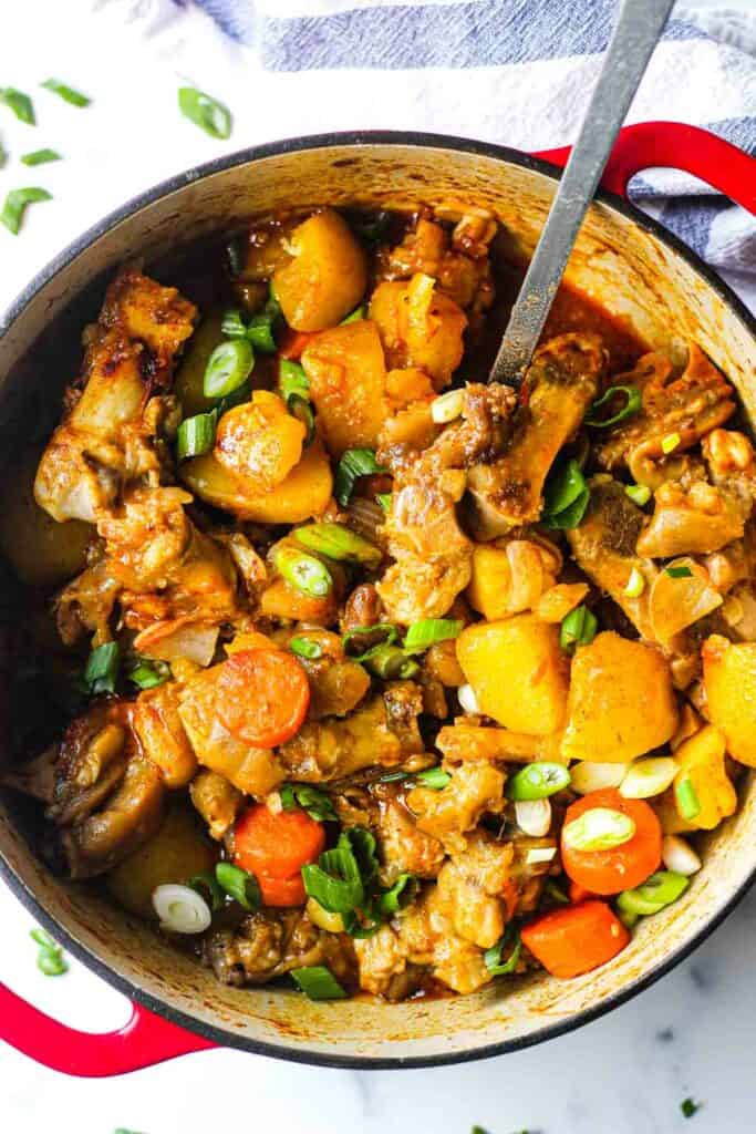 cooked pork feet stew with vegetables in the pot with chopped green onions on top