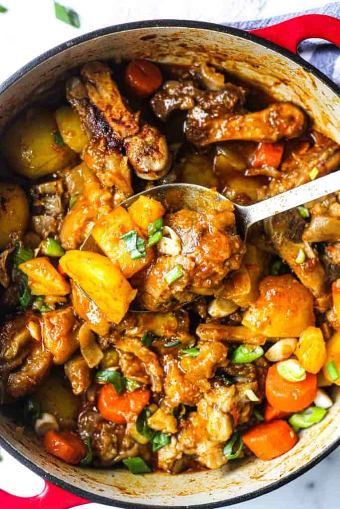 cooked pig feet stew with vegetables in the pot with chopped green onions on top