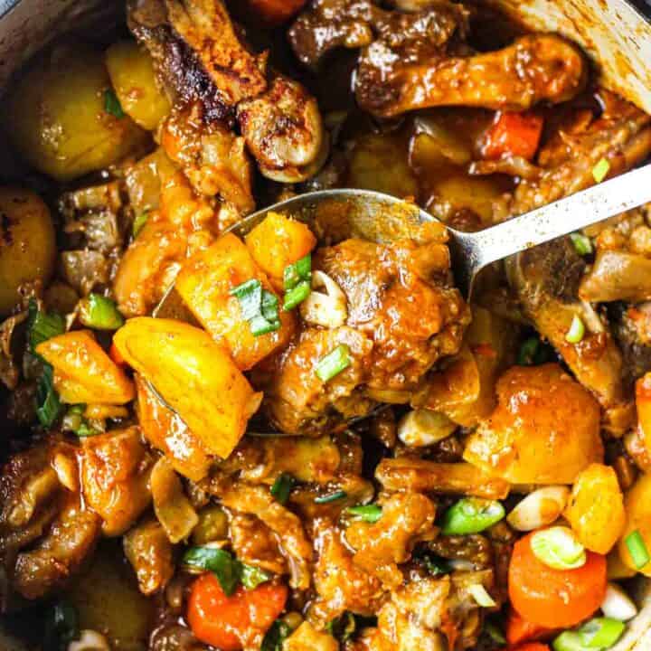 cooked pig feet stew with vegetables in the pot with chopped green onions on top