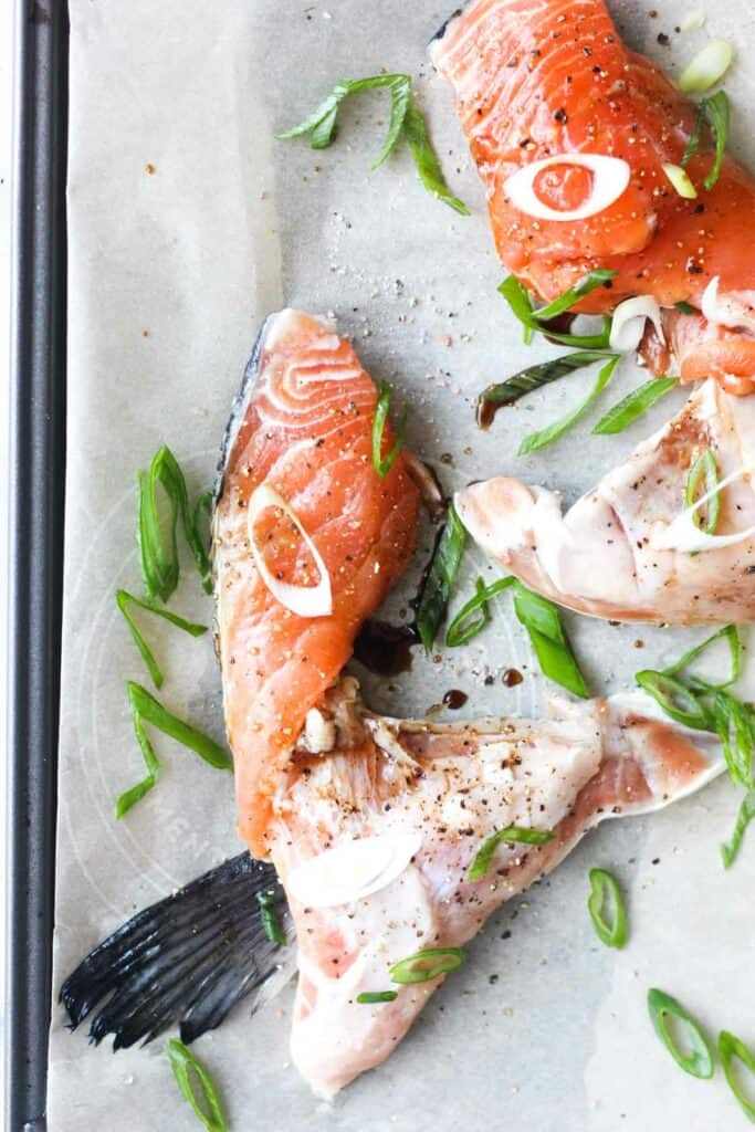 raw salmon kama with chopped scallions on the parchment paper