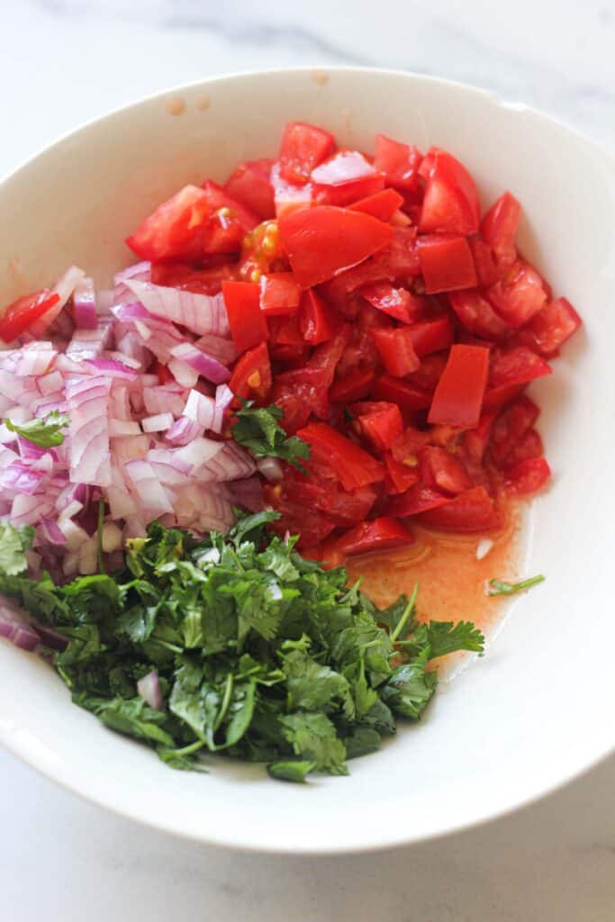 chopped tomatoes, cilantro and red onions in a bowl
