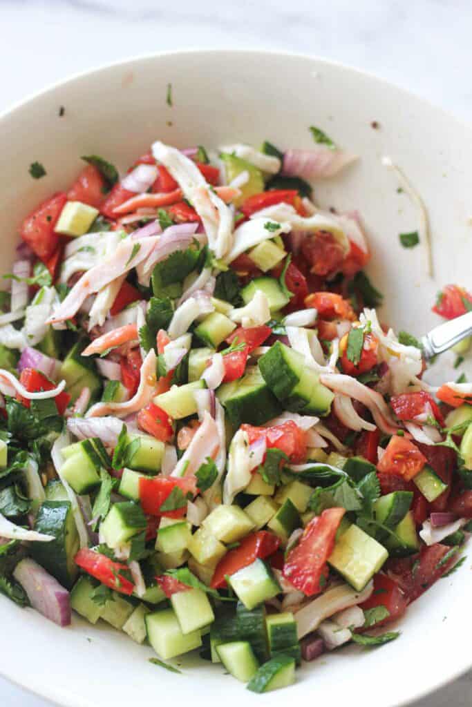 mixing chopped cucumbers, onions, tomatoes and cilantro with lime juice