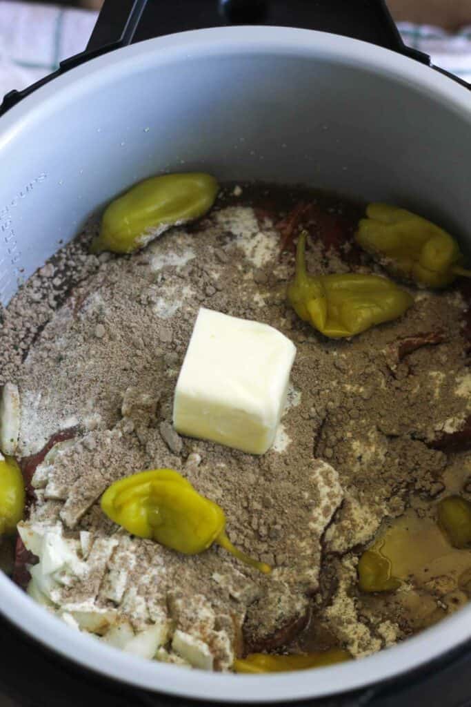 adding pepperonchini and ranch dry mix to the pot roast