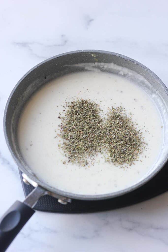 white sour cream souce with dried herbs on top in the pan