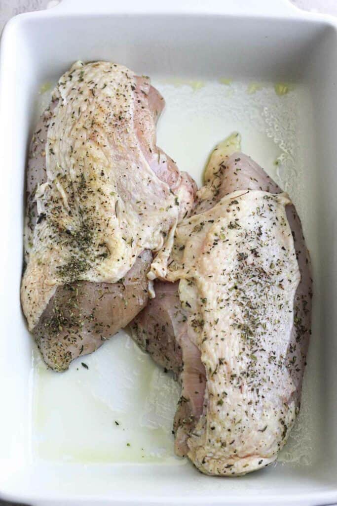 seasoned raw chicken breasts skin on in the baking dish