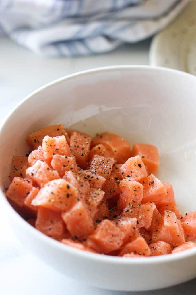 chopped raw salmon with salt and pepper in the bowl