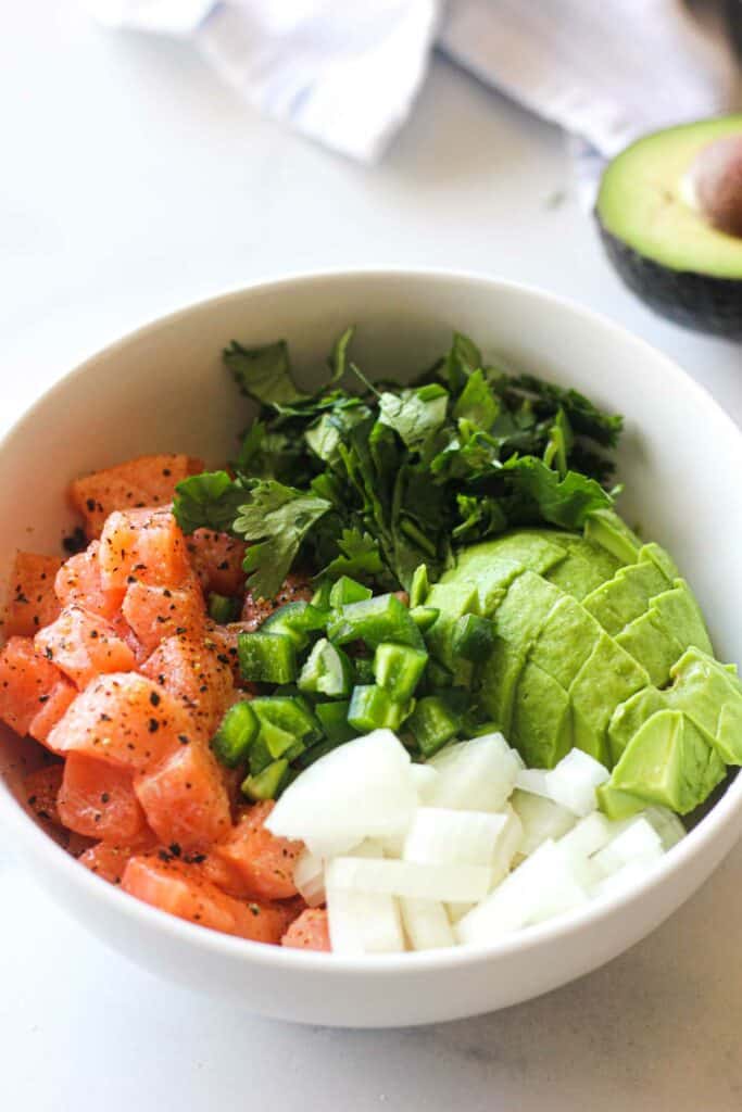 chopped jalapeno, onions, salmon, cilantro and avocado in the white bowl