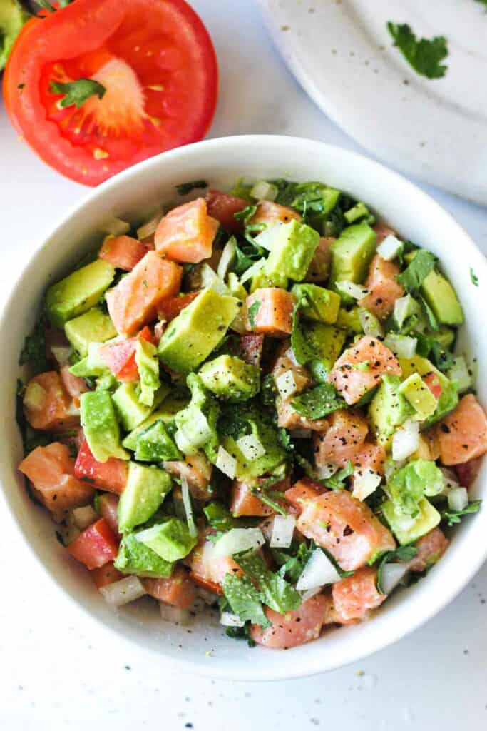 top view of raw salmon avocado ceviche in a white bowl