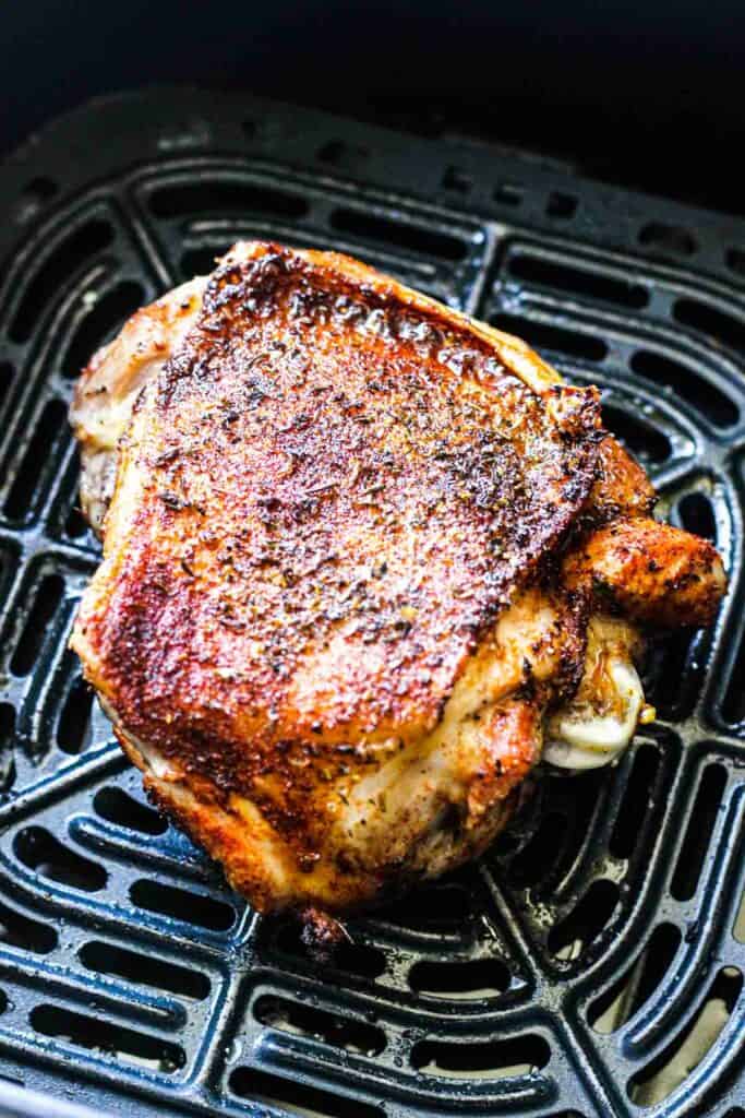 brown crispy bird skin in the air fryer in the middle of cooking