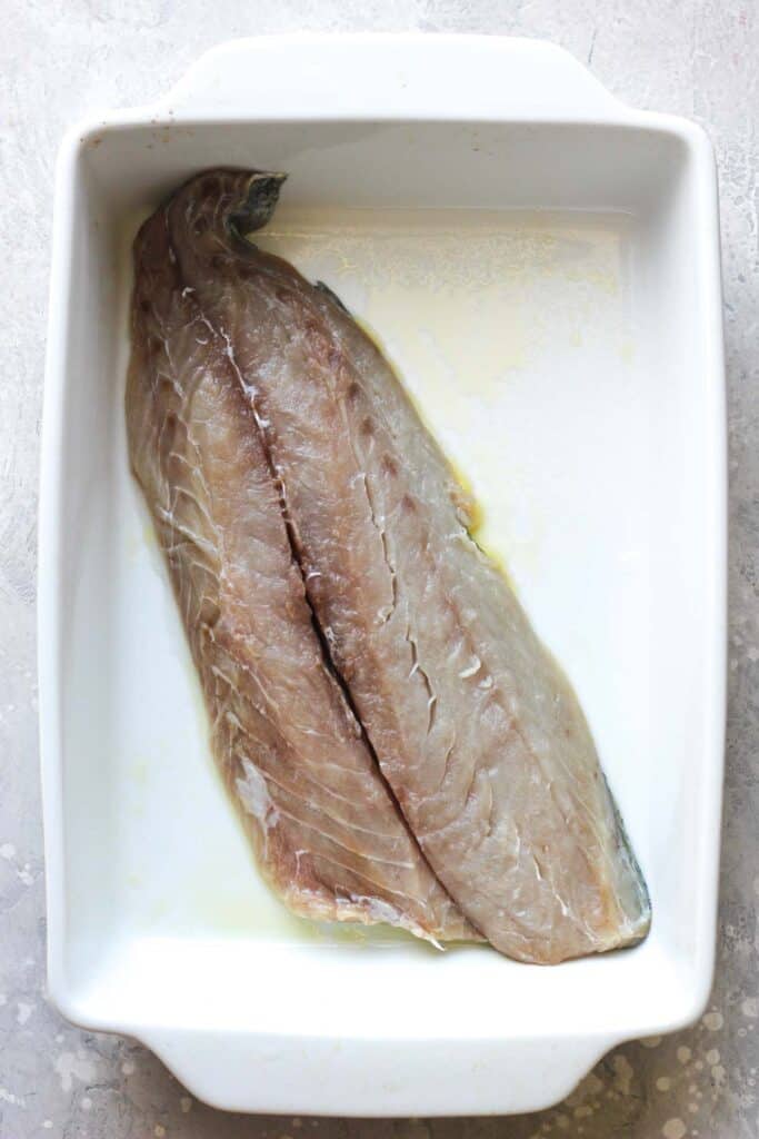 raw fish fillet in a white baking dish