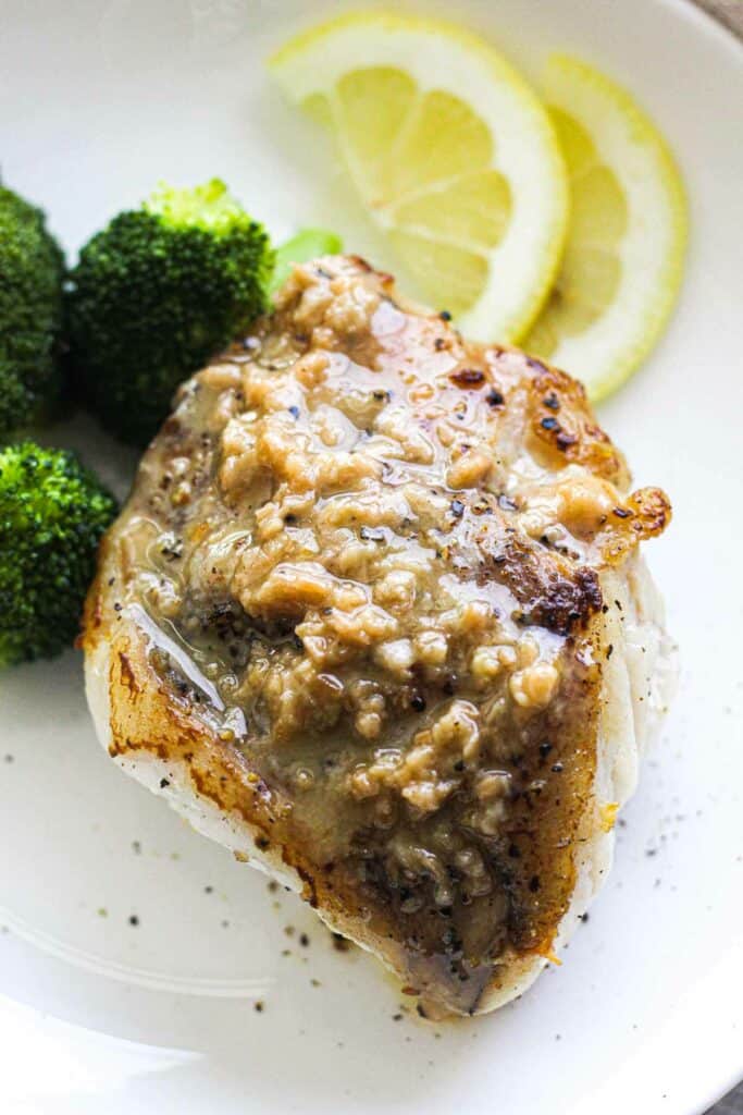 fish fillet with sauce and steamed broccoli and lemon slices