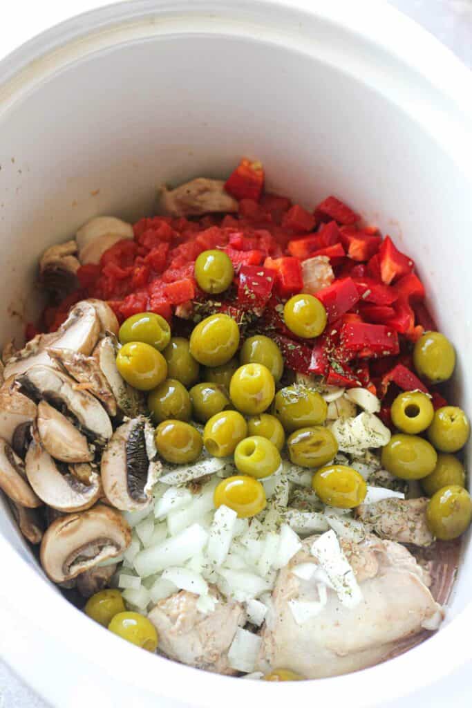 adding green pitted olives to the crock pot on top of other ingredients