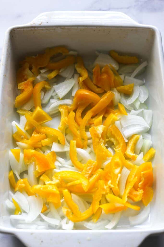 shopped white onions and yellow bell pepper in a baking dish