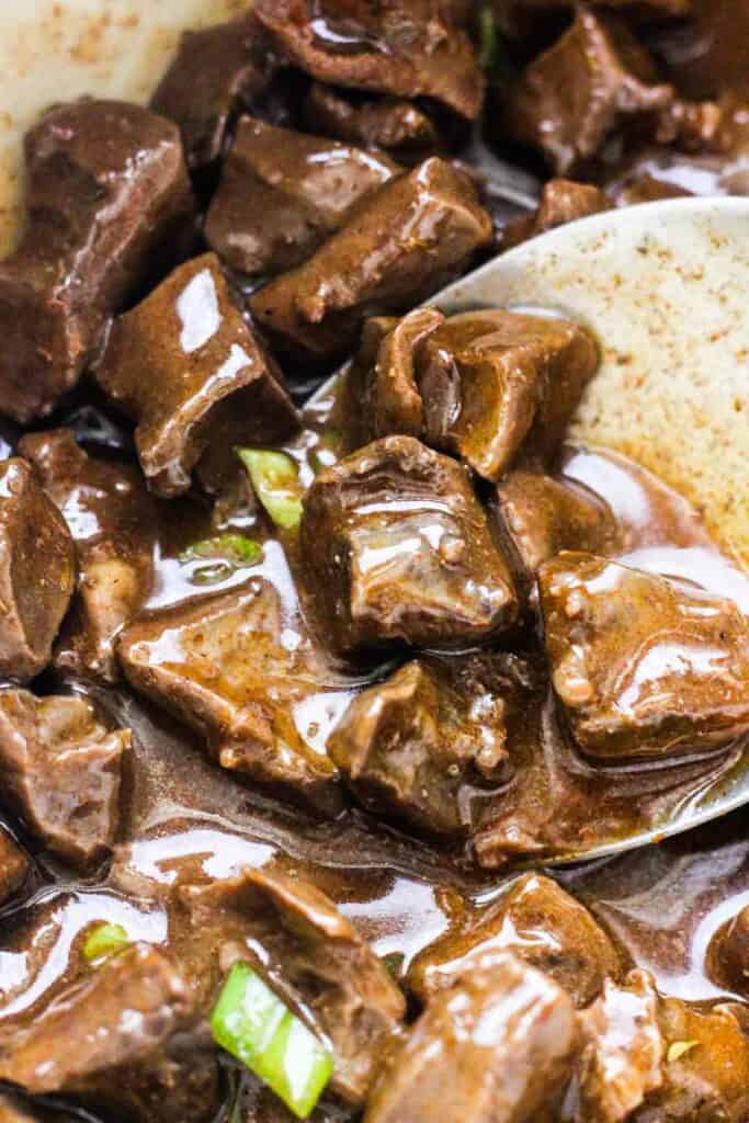 lamb heart stew with chopped scallions in a pot with sauce