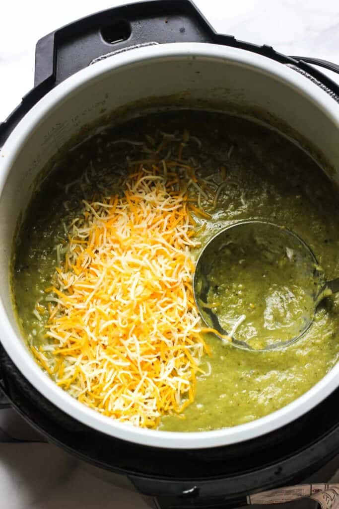 adding shredded cheddar cheese in to the rocooli soup in pressure cooker