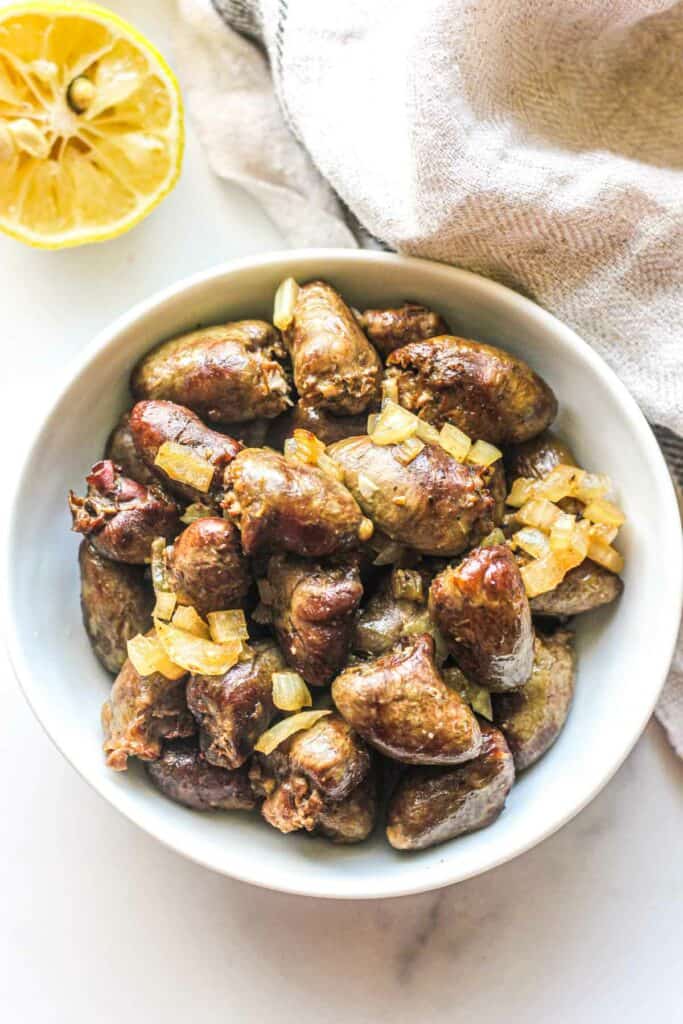 air fryied chicken hearts with onions in a white bowl