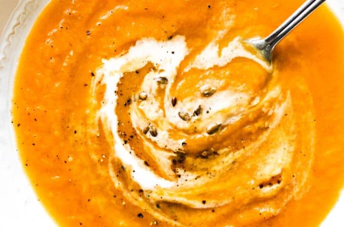 creamy squash soup with black pepper on top and a dash of heavy cream