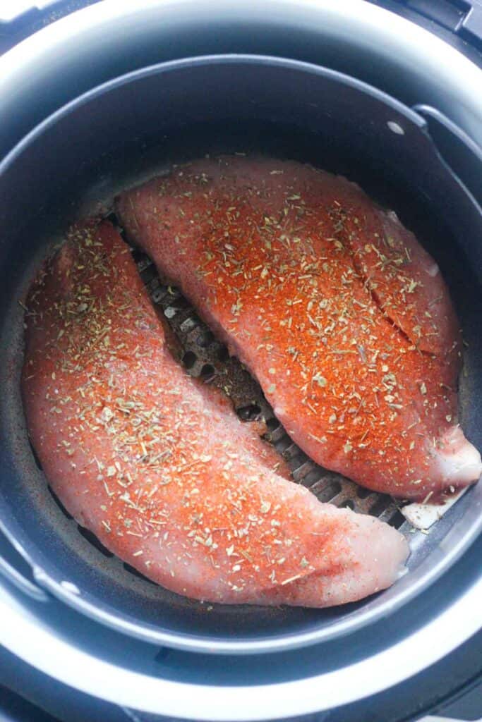 raw seasoned poultry inside the air fryer basket before cooking
