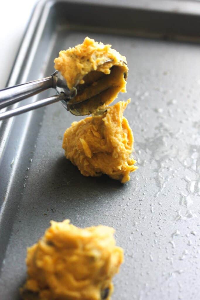 scooping pumpkin ricotta cookies on to the greased cookie sheet
