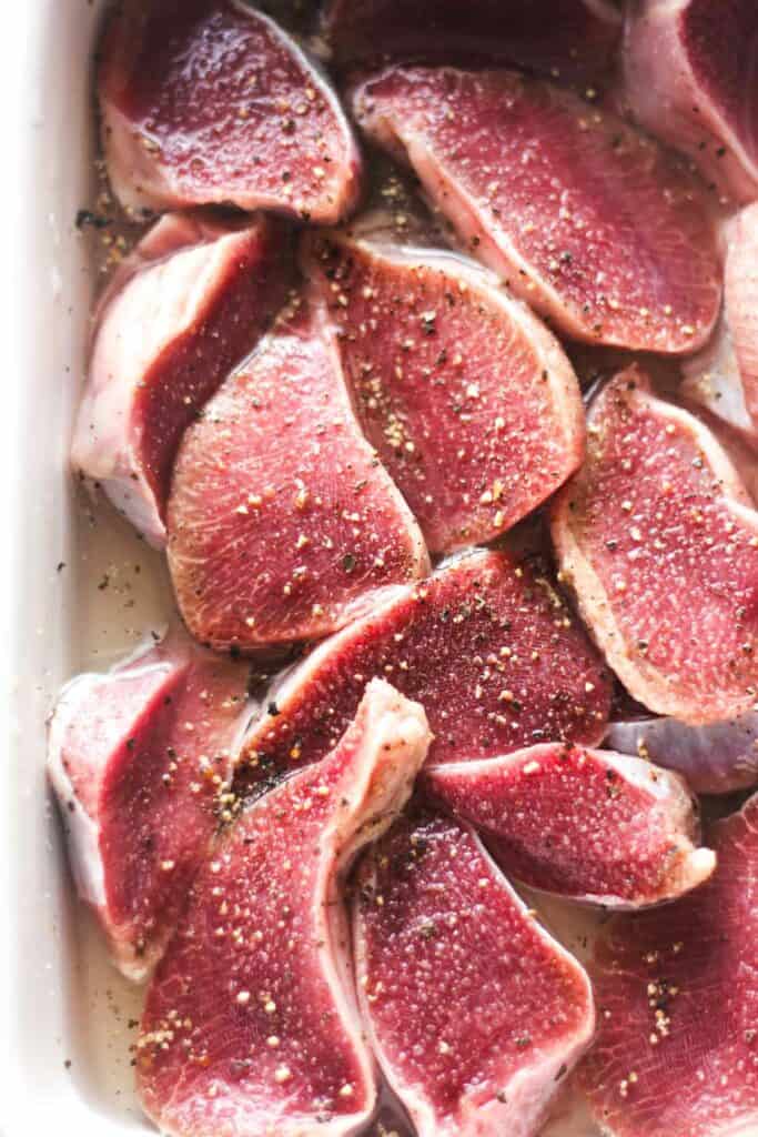 raw sliced giblets with salt and black pepper in the white baking dish