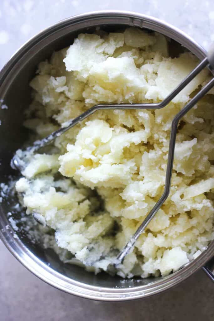 mashing potatoes with the tool in the pot