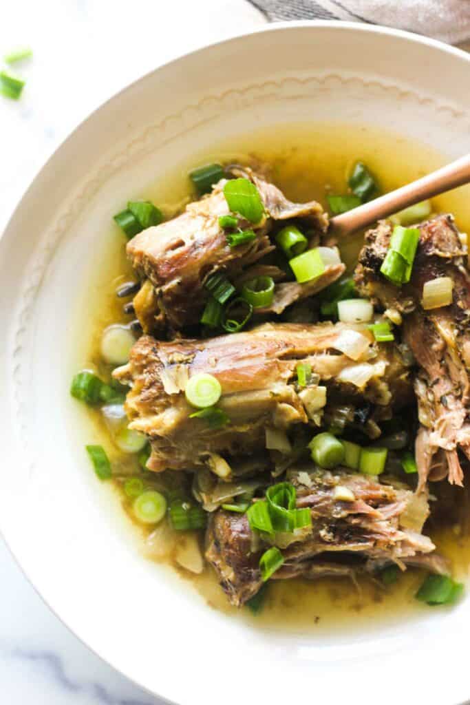 slow cooker turkey necks with green onions on a white plate