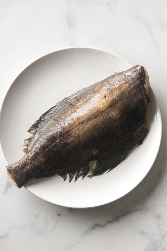 raw whole white fish on white plate