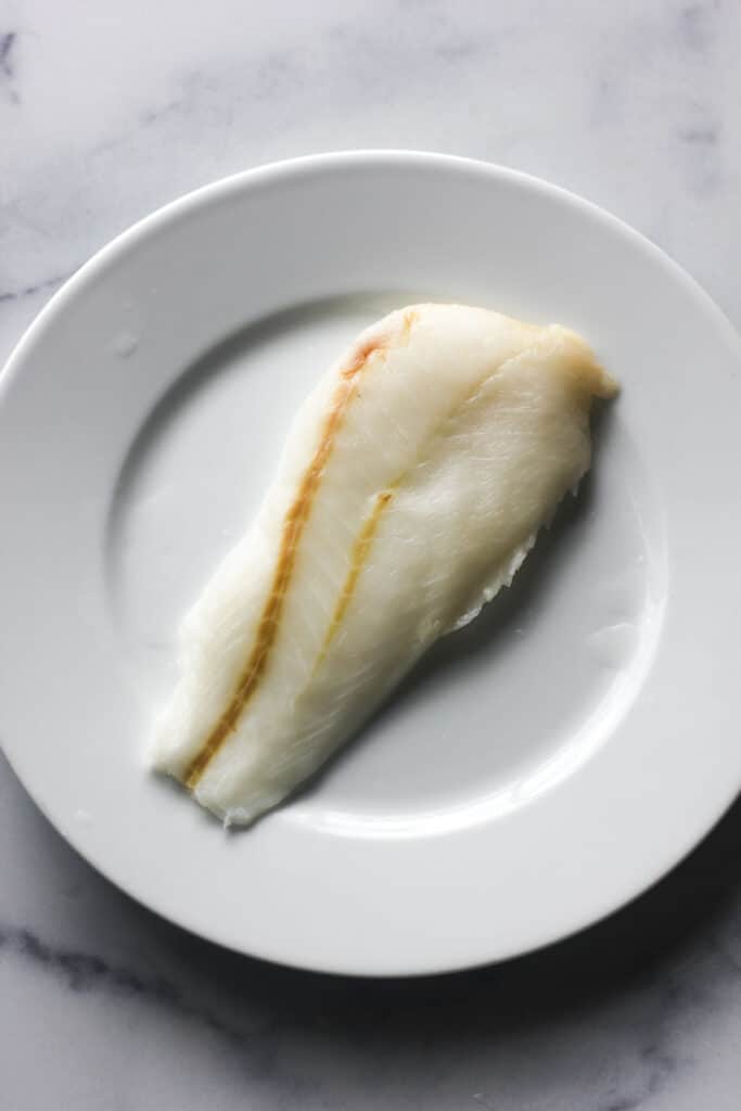 raw white fish on a white plate