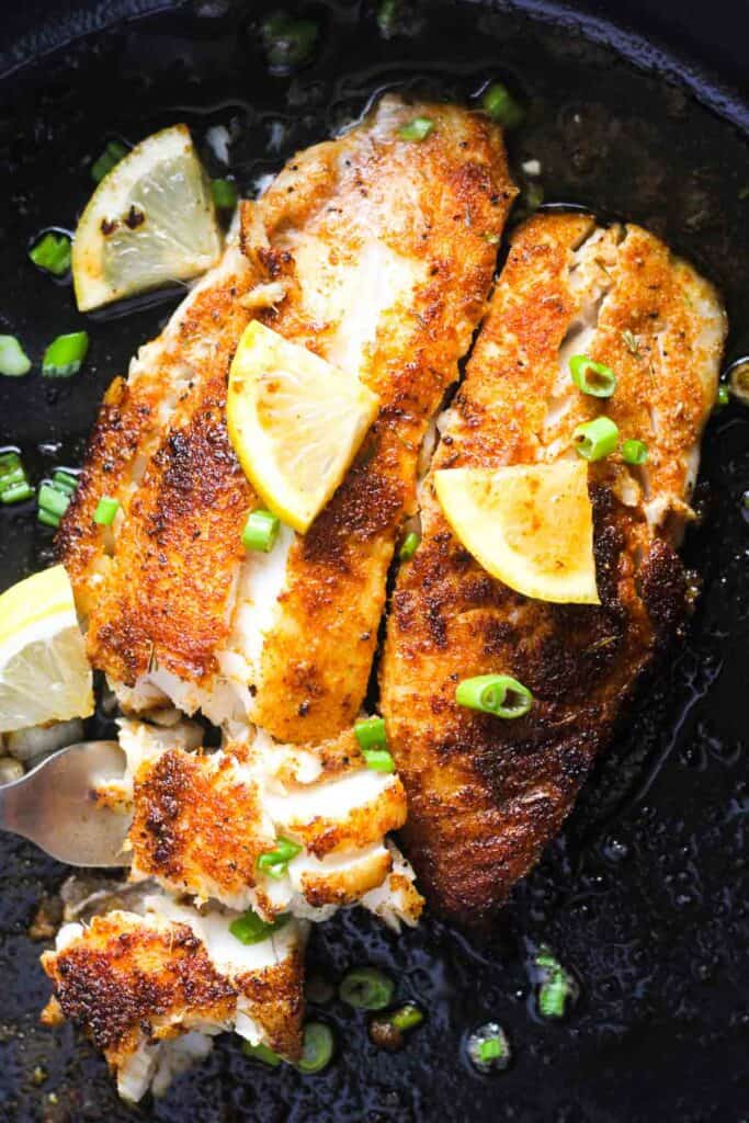 blackened blackfish with green onions in the skillet