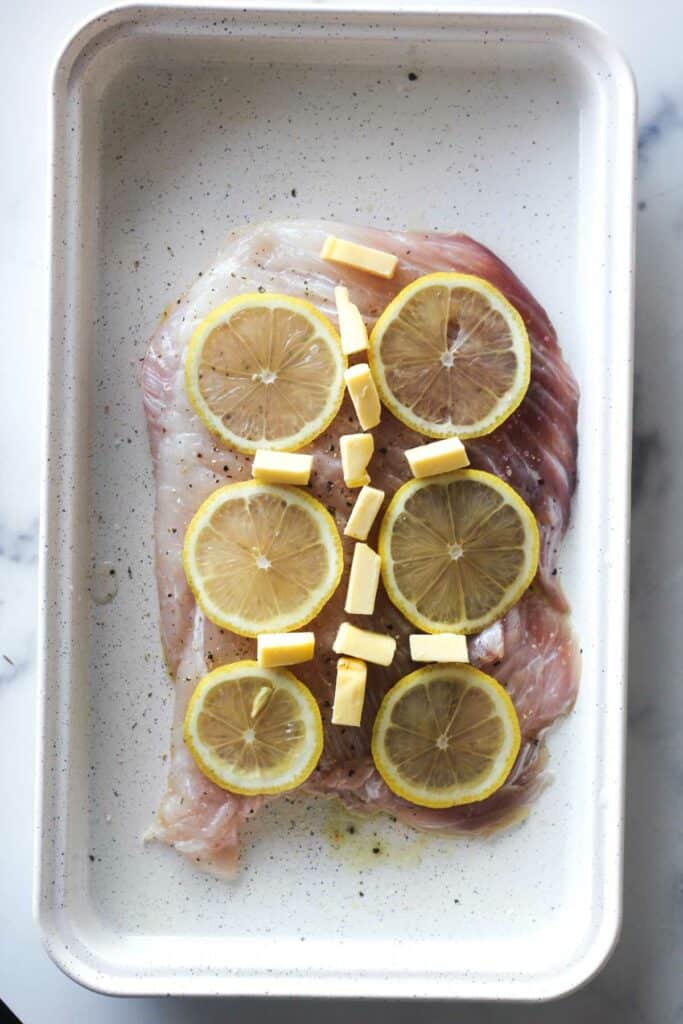 raw fish with lemon slices and butter on top