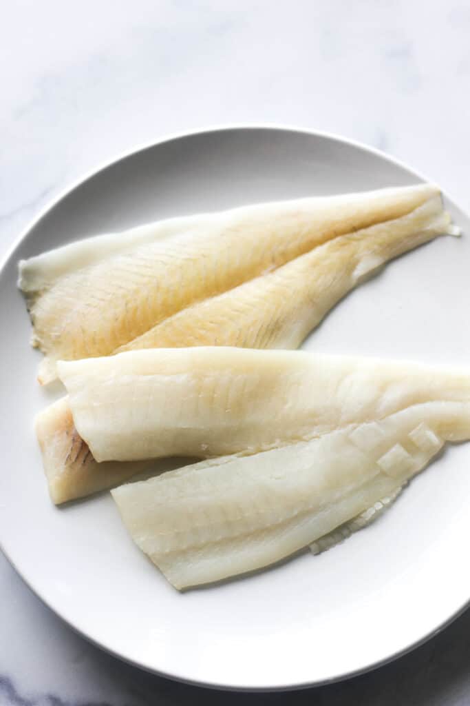 raw white fish fillet on the white plate