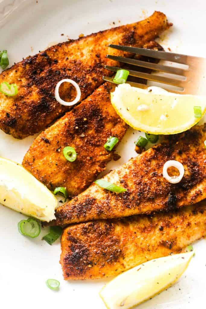 cooked white fish with lemon and green onions