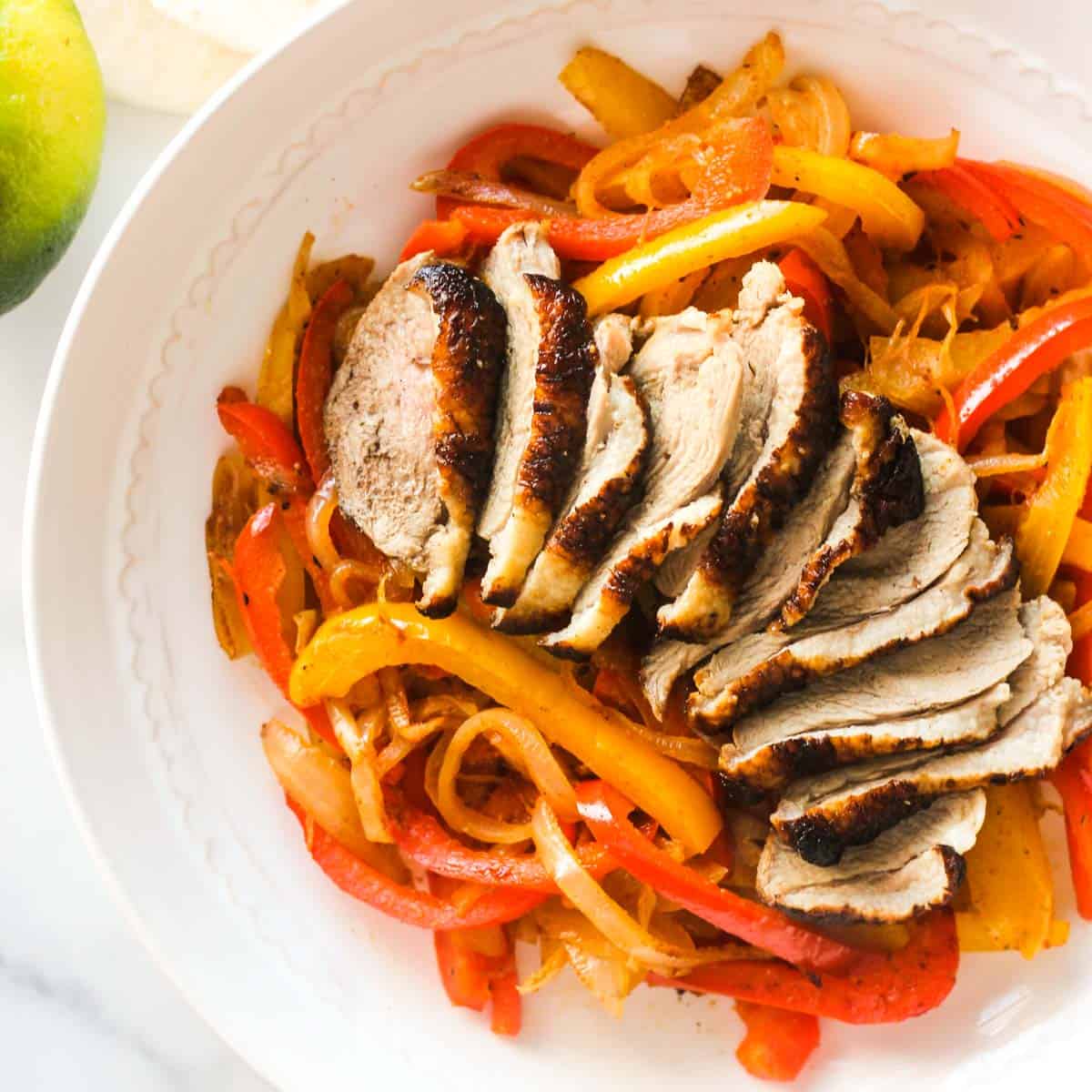 sliced duck breast on top of bell peppers and sliced onions