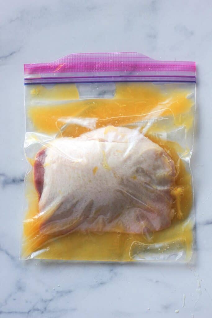 raw duck breast marinating in orange juice in ziplock bag