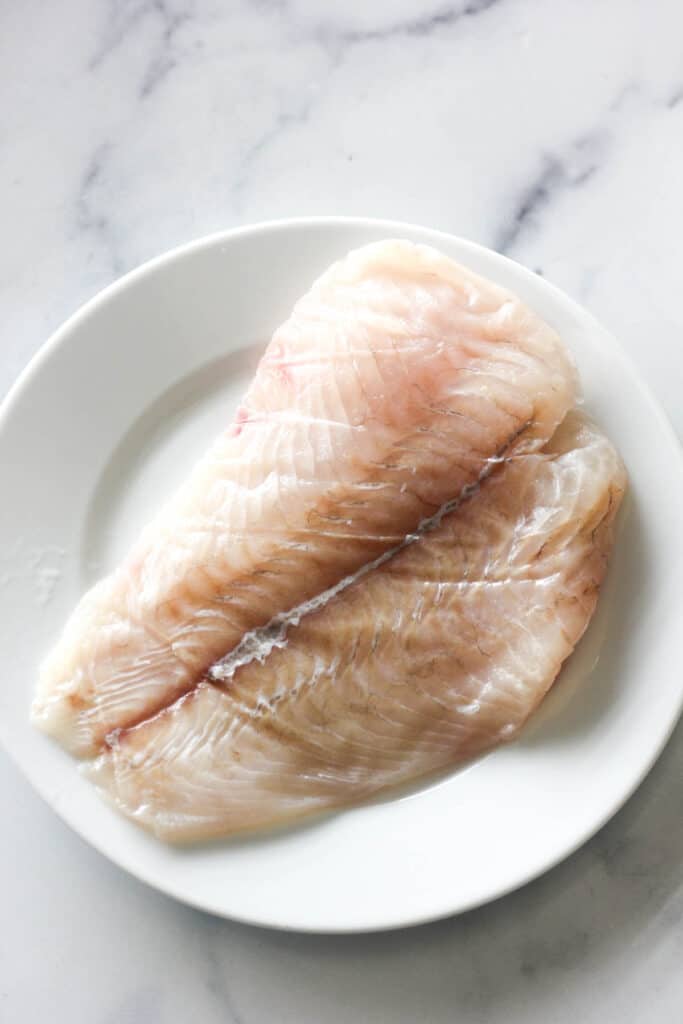 raw fluke fish fillet on a white plate