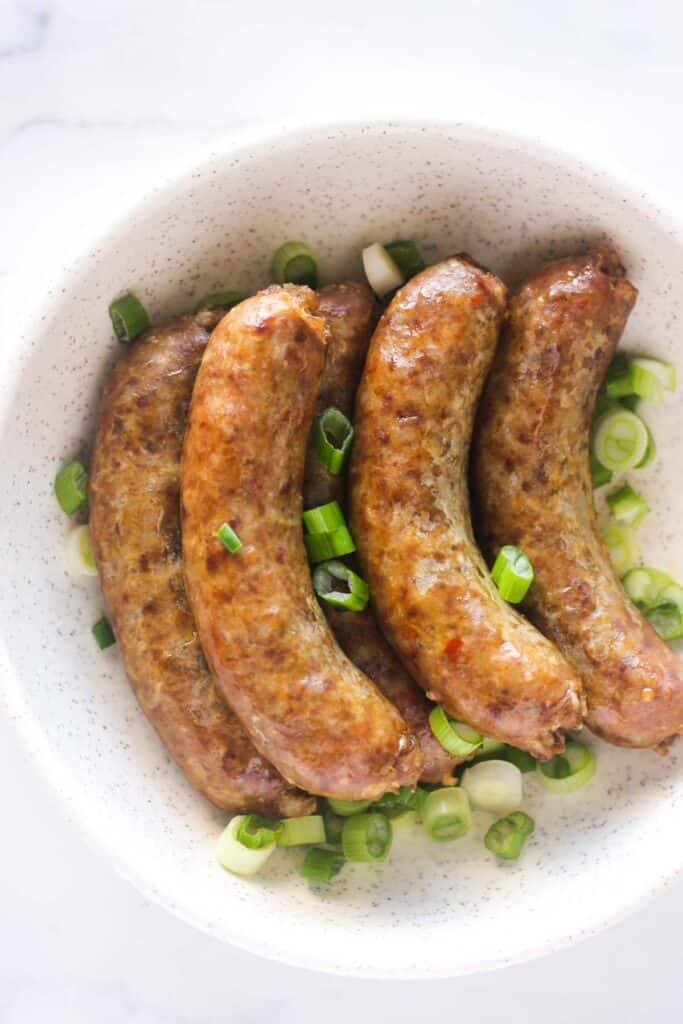 cooked sausage served on the plate with chopped green onions