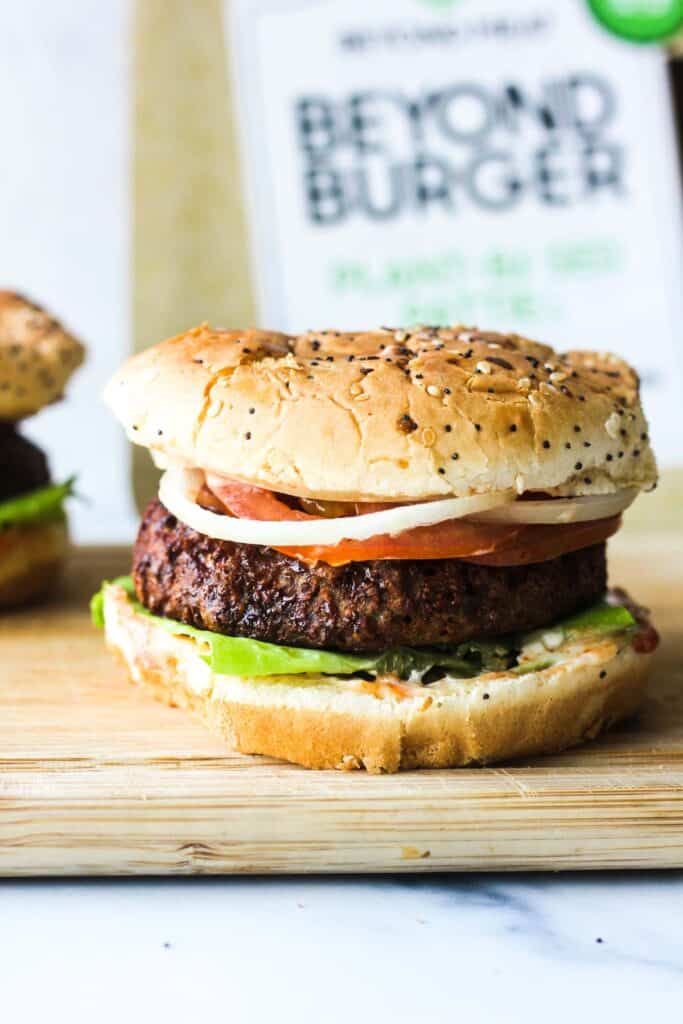 veggie beyond burger with lettuce, tomatoes, bun and onions on a cutting board