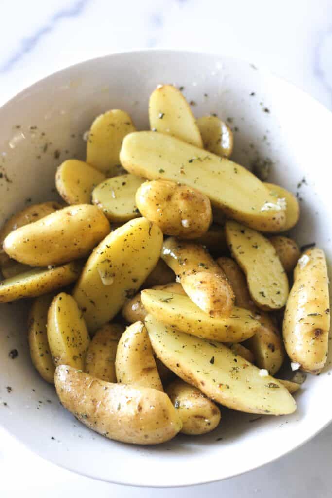 raw seasoned potatoes with oil in a white bowl